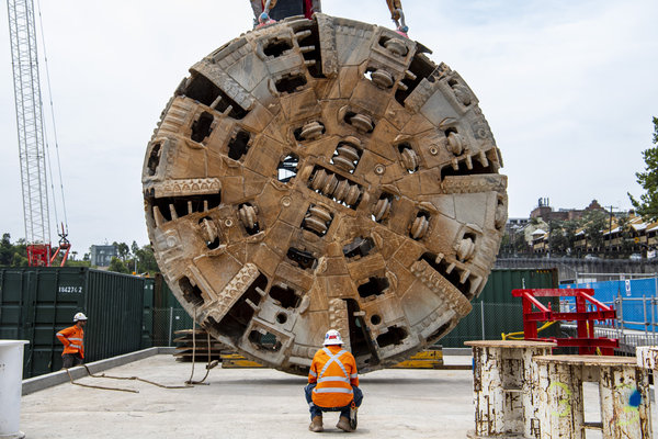An on the ground view of two construction workers inspecting the Cutterhead Lift of  Tunnel Boring Machine (TBM) Mum Shirl at Sydney Metro's at Barangaroo site. 