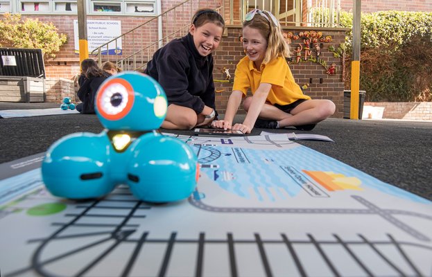 Two students from Petersham Public School smiling behind the dash robot that is sitting on top of an alignment map