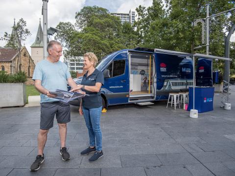 Sydney Metro worker talking to a member of the community in front of the Sydney Metro van