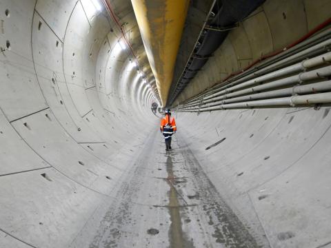 Worker in hi-vis gear walking through a tunnel