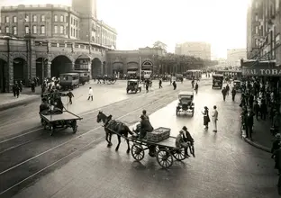 A photo from the City of Sydney Archives: 051080, showing commuters outside of Central station in cars and horse drawn carriages along south of Pitt Street.