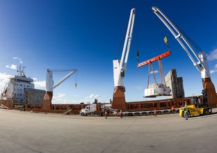 A massive crane lifts part of a TBM off a boat at Newcastle Port.