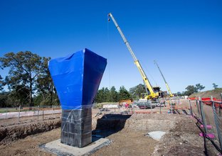 Skytrain pier column wrapped in blue tarp is under construction.