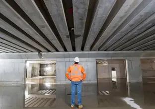 A view from behind showing a man in orange high-vis shirt and hard hat looks on at the Chatswood Dive Cassette Structure with his hands on his hips.