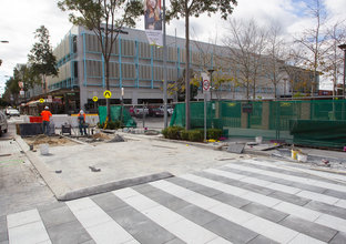 Rouse Hill construction site is viewed from outside the hoarding on a pedestrian crossing.