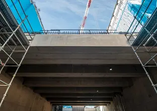 View from below of platforms installed at Waterloo Station. A large crane and sky is in the background.