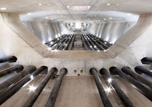 An on the ground view looking inside the tunnel where the skytrain will run showing 12 rows of steel cables running down the tunnel, the skytrain will be held together by 1,400km of steel cables. 