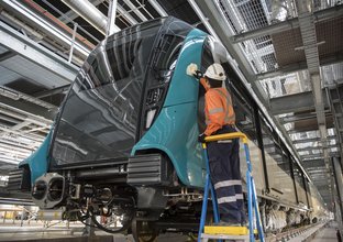 An upward facing view of a construction worker polishing the new Sydney Metro Train after it has been unwrapped.