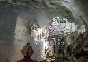 A large Roadheader is working inside the tunnels underneath Bligh Street while a construction worker looks on.