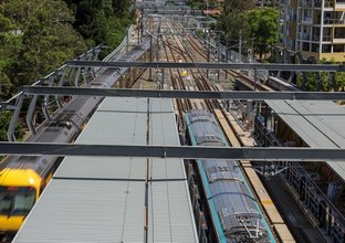 An arial shot looking down on the station platform as a Sydney Metro Train arrives at the platform next to a Sydney Trains train at Chatswood Station. 