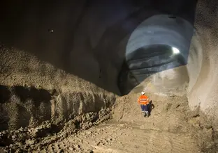 An on the ground view from inside the cavern as a construction worker inspecting the tunnel with their head torch shining a light to the top of the tunnel as tunnelling commences at Sydney Metro's Pitt Street North Castlereagh Cavern site.