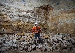 An on the ground view showing  a construction worker standing in front of a pile of sandstone that has been taken down as construction continues at Sydney Metro's Martin Place Station.