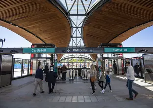 A view of Castle Hill Station entrance at the top of the escalators with a crowd of people walking around.