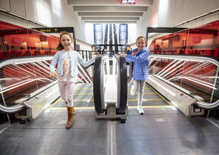 Two young girls stand at the top of the escalators at Castle Hill Station.
