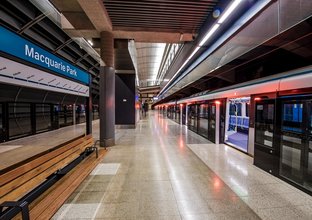 An artist's impression from the platform behind the screen safety doors opened as a train has stopped at the platform showing the platform benches at Sydney Metro's Macquarie Park Station.