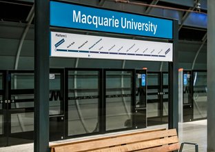 A close up shot of the signage displayed on the platform behind the screen safety doors above a bench at Sydney Metro's Macquarie University.