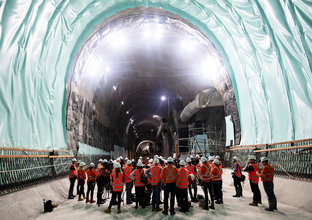 A group of people in full personal protective equipment conducting a site visit inside Sydney Metro's Martin Place Station tunnel. 