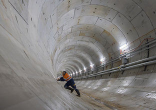 An on the ground view of a construction worker leaning into concrete panels inside Sydney Metro's Harbour Tunnel 