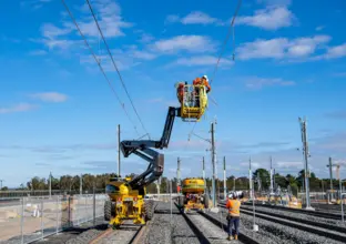 A wide angle view of construction workers on a cherry picker lift as the overhead works continue as part of the expansion of the Sydney Metro Trains Facility in Rouse Hill.