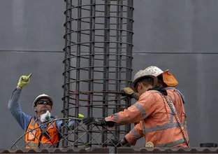 Three construction workers in high viz holding metal piling used to complete piling work at the Northern Connection construction site.