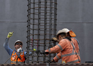 Three construction workers in high viz holding metal piling used to complete piling work at the Northern Connection construction site.