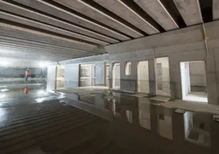 A view inside the cassette structure at Chatswood Dive Site. A puddle of water shows reflections on the ground.