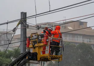 Two construction workers on a cherry picker are working on the overhead gantries for track realignment