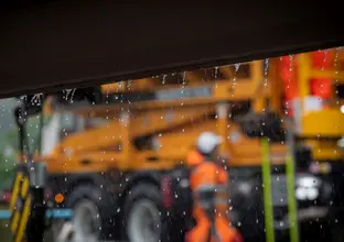 Image of rain falling with blurred out-of-focus heavy machinery in the background.