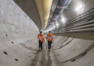An on the ground view of two construction workers walking through Chatswood Drive Tunnels 