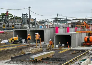 Construction workers in full personal protection equipment work on the aqueduct construction site at Sydenham.