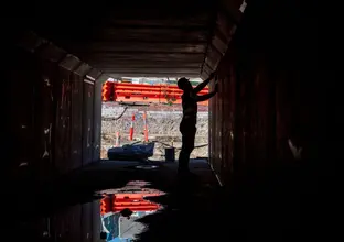 An on the ground view looking at a construction worker inside a tunnel