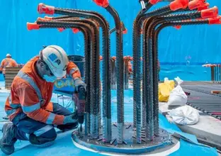 A construction worker in high viz is drilling into metal pilings at the Waterloo construction site. 