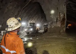 A view from behind a construction worker in orange high-vis looking at the work being completed inside Barangaroo Crossover cavern.