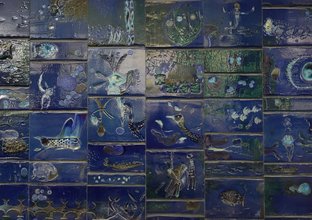 A close up view of old blue annand mural tiles with various etchings and patterns on them.
