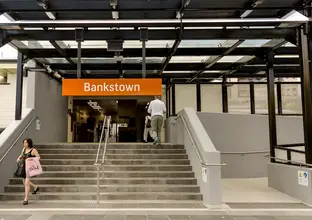 Commuters walking up and down the stairs at the entrance of Sydney Train's Bankstown Station. 