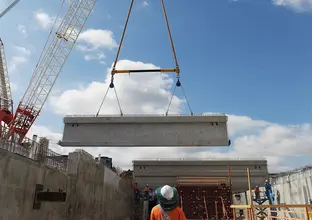 Large concrete beams are being installed by a crane in the station box of the Bella Vista Station construction site.