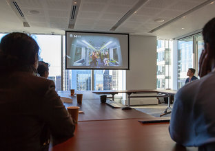 Several people looking at a presentation on screen in a boardroom.