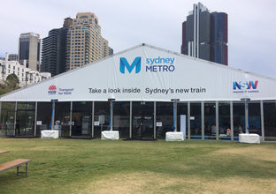 A large Sydney Metro branded marquee displaying the words 'take a look inside Sydney's new train' which was displayed at Barangaroo Reserve.