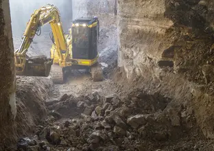 A yellow excavator digs up spoil inside the Central Station construction site.