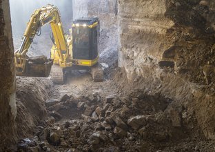 A yellow excavator digs up spoil inside the Central Station construction site.