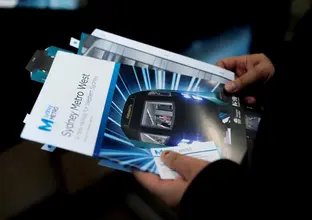 A close up shot of a community member holding some Sydney Metro West flyers received at the community information centre at Westmead Hospital. 