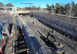 An aerial view of Norwest Station box under construction. Heavy machinery and construction workers are inside the station box.