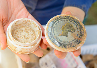 A person's hands holding an old cherry flavoured toothpaste jar that was uncovered at White Hart Inn site.