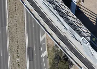 A bird's eye view of Sydney Metro's Windsor Road bridge being constructed, there are cars traveling on the road below.