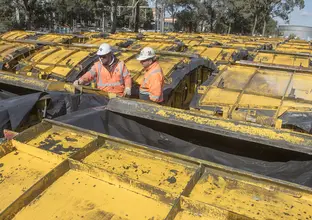 Two construction workers inspecting the moulds of the Sydney Metro trains lined up in the background.