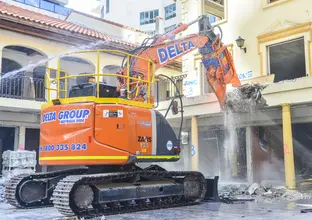 An on the ground view showing the Excavator attachment the pulveriser as it begins demolition of a building at a Sydney Metro construction site. 