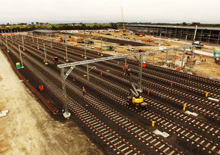 An arial view looking down at the ten tracks being laid at the Sydney Metro Train Facility at Rouse Hill with construction happening in the background.