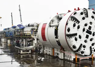 A wide angle of a TBM under construction outdoors in the rain.