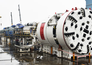 A wide angle of a TBM under construction outdoors in the rain.