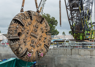 TBM2 Florence cutterhead is being retrieved from the dive site by a large crane.